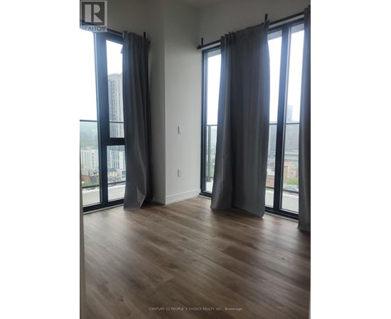 A room with wooden floors and large windows with curtains.