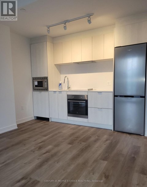 A kitchen with white cabinets and a wooden floor.