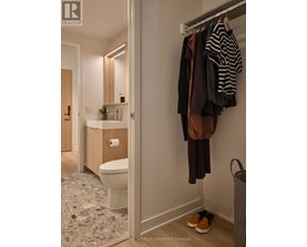 A bathroom with a toilet, sink, and clothes hanging up.