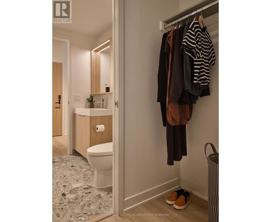 A bathroom with a toilet, sink, and clothes hanging up.