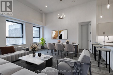 A living room with a grey sofa, a coffee table, and a dining table with chairs.
