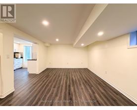 A large, empty room with wooden flooring and white walls.