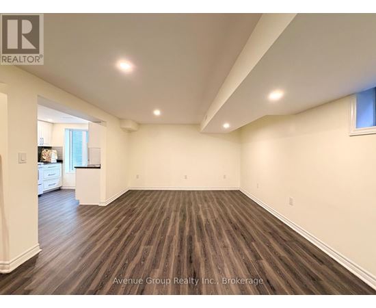A large, empty room with wooden flooring and white walls.