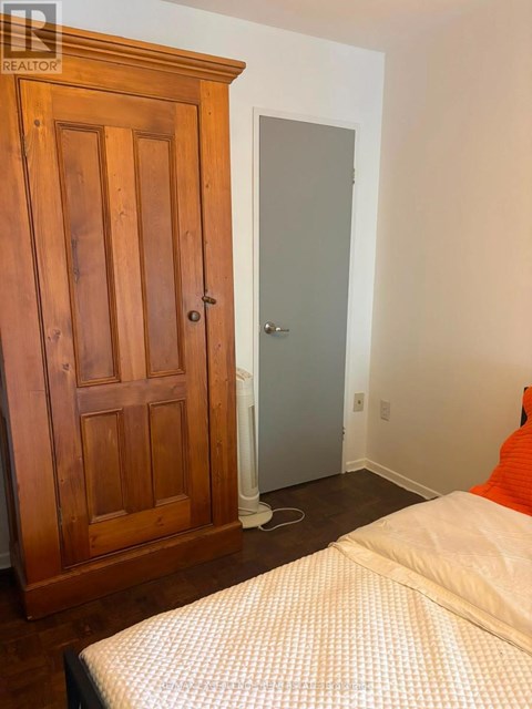 A bedroom with a bed, wooden wardrobe and a door.
