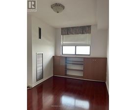 A room with a wooden floor and a window with blinds.