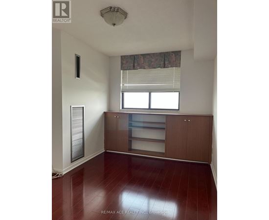 A room with a wooden floor and a window with blinds.