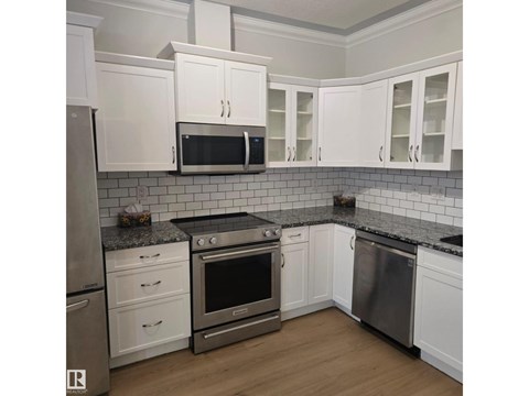 A kitchen with white cabinets and stainless steel appliances.