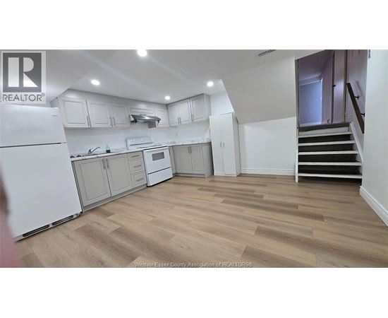 A kitchen with white appliances and wooden floors.