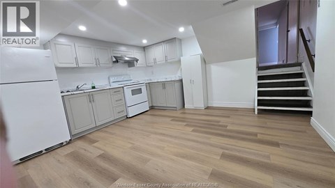 A kitchen with white appliances and wooden floors.