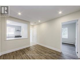 A spacious room with wood flooring and white walls.