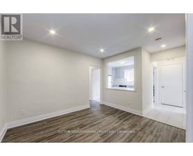 A spacious room with wood flooring and white walls.