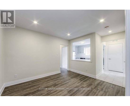 A spacious room with wood flooring and white walls.