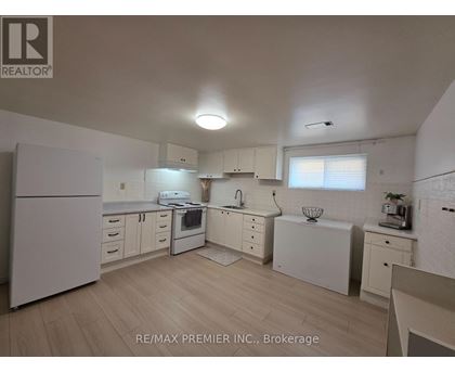 A white kitchen with wooden floors and white appliances.