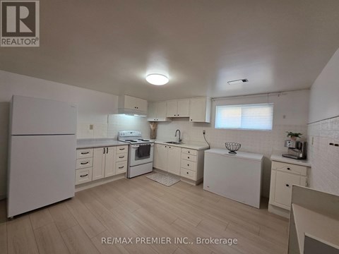 A white kitchen with wooden floors and white appliances.