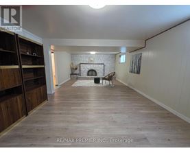 A spacious room with a fireplace and wooden flooring.
