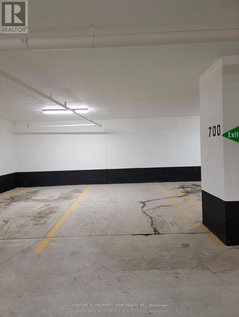 A white and black parking garage with a green exit sign.