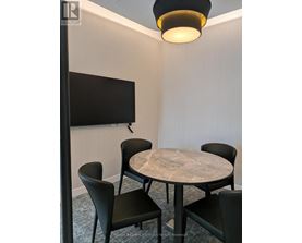A conference room with a table, chairs, and a television.