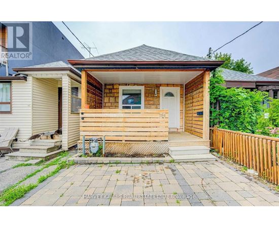 A small wooden house with a front porch and a white door.