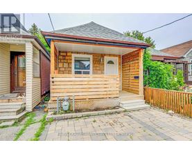 A small wooden house with a front porch and a mailbox on the front step.