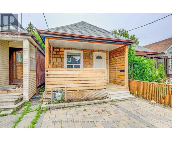 A small wooden house with a front porch and a mailbox on the front step.