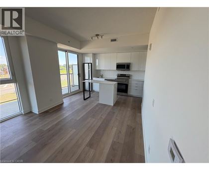 A well-lit, spacious kitchen and living room with wood flooring and white walls.
