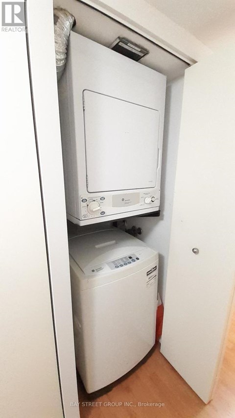 A white dryer is in a small closet.