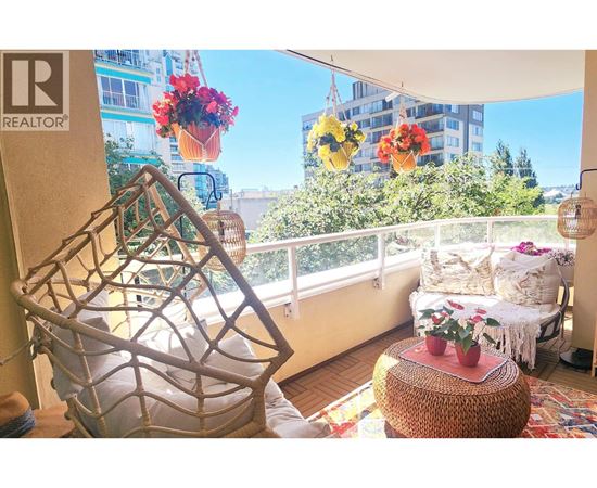 A balcony with a chair and a table with flowers.