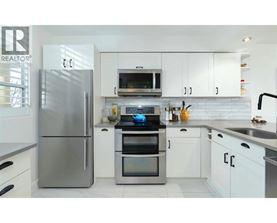 A modern kitchen with a stainless steel refrigerator and white cabinets.