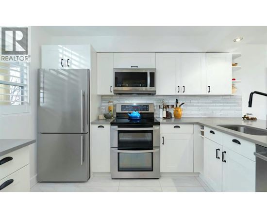 A modern kitchen with a stainless steel refrigerator and white cabinets.