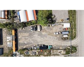 An aerial view of a construction site with a large orange and white cylindrical tank in the background.