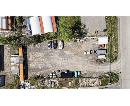 An aerial view of a construction site with a large orange and white cylindrical tank in the background.
