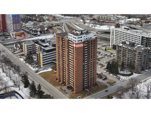 A tall brown building is in the middle of a snowy street.