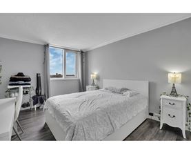 A bedroom with a large bed, a chair, and a small table with a lamp.