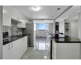 A kitchen with white cabinets and black countertops.