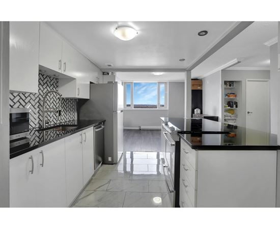 A kitchen with white cabinets and black countertops.