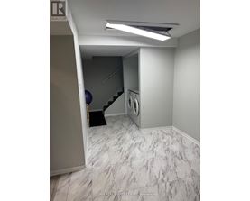 A hallway with a washing machine and dryer in the corner.