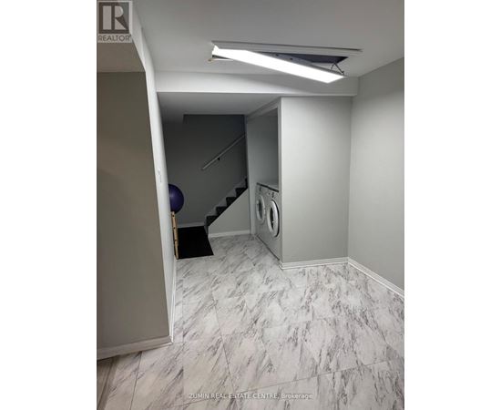 A hallway with a washing machine and dryer in the corner.