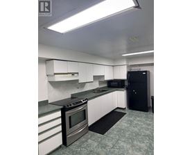 A kitchen with a black fridge and a black mat on the floor.