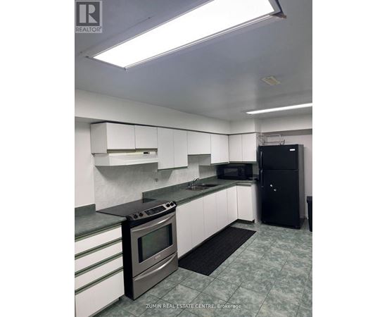 A kitchen with a black fridge and a black mat on the floor.