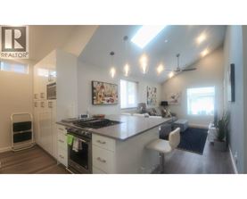 A modern kitchen with a large island and a refrigerator on the left.