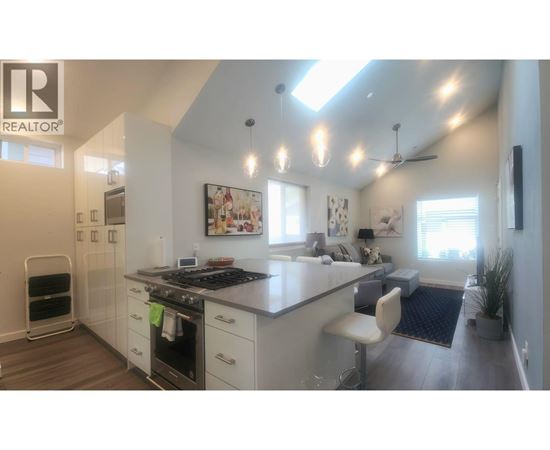 A modern kitchen with a large island and a refrigerator on the left.