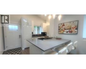 A modern kitchen with a white countertop and a painting on the wall.