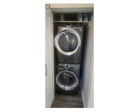 A washing machine is sitting in a small alcove.