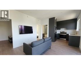 A living room with a grey couch and a television on the wall.