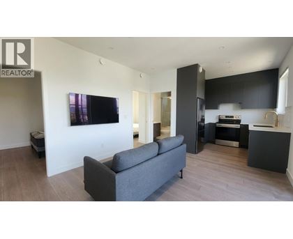 A living room with a grey couch and a television on the wall.