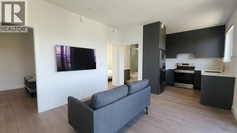 A living room with a grey couch and a television on the wall.