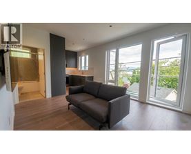 A living room with a grey couch and a large window.