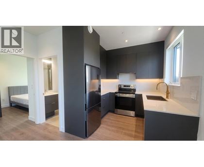 A modern kitchen with dark cabinets and a stainless steel refrigerator.