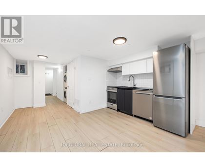 A kitchen with a refrigerator, oven, and sink.