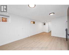 A spacious room with wooden flooring and white walls.